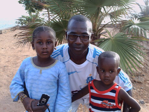Un homme, une fillette et un jeune enfant devant des palmiers