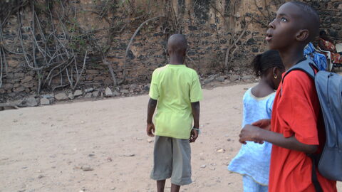 Trois enfants sur un chemin de terre, vus de dos et de profil
