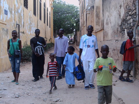 Groupe marchant dans une ruelle entre des maisons aux murs ocres