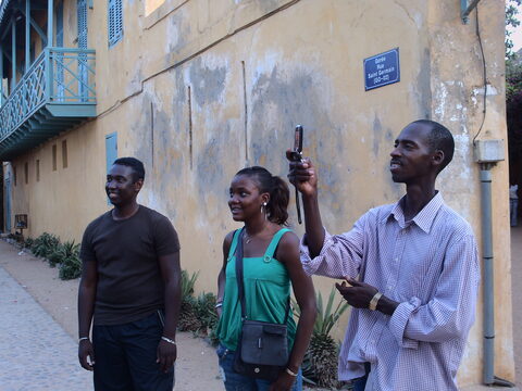 Trois personnes devant un mur jaune portant une plaque de rue