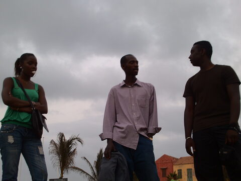 Trois jeunes adultes debout, ciel nuageux et palmier