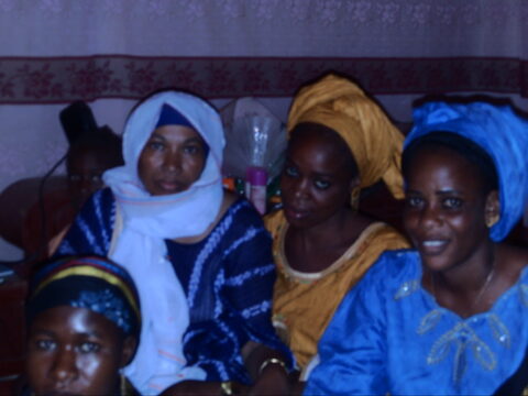 Femmes assises à l'intérieur, enfants assis au sol devant elles