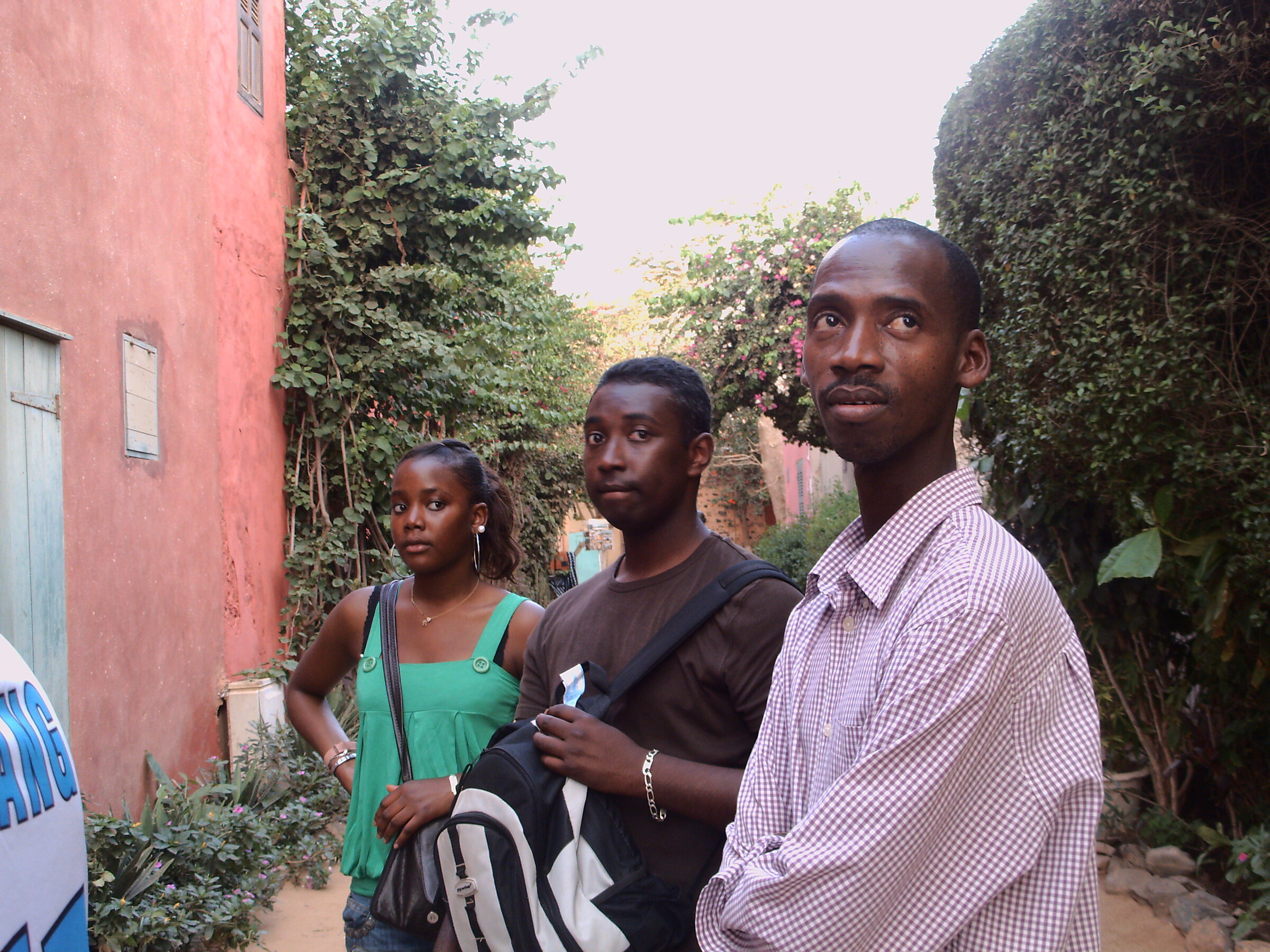 Trois jeunes adultes dans une ruelle bordée de végétation
